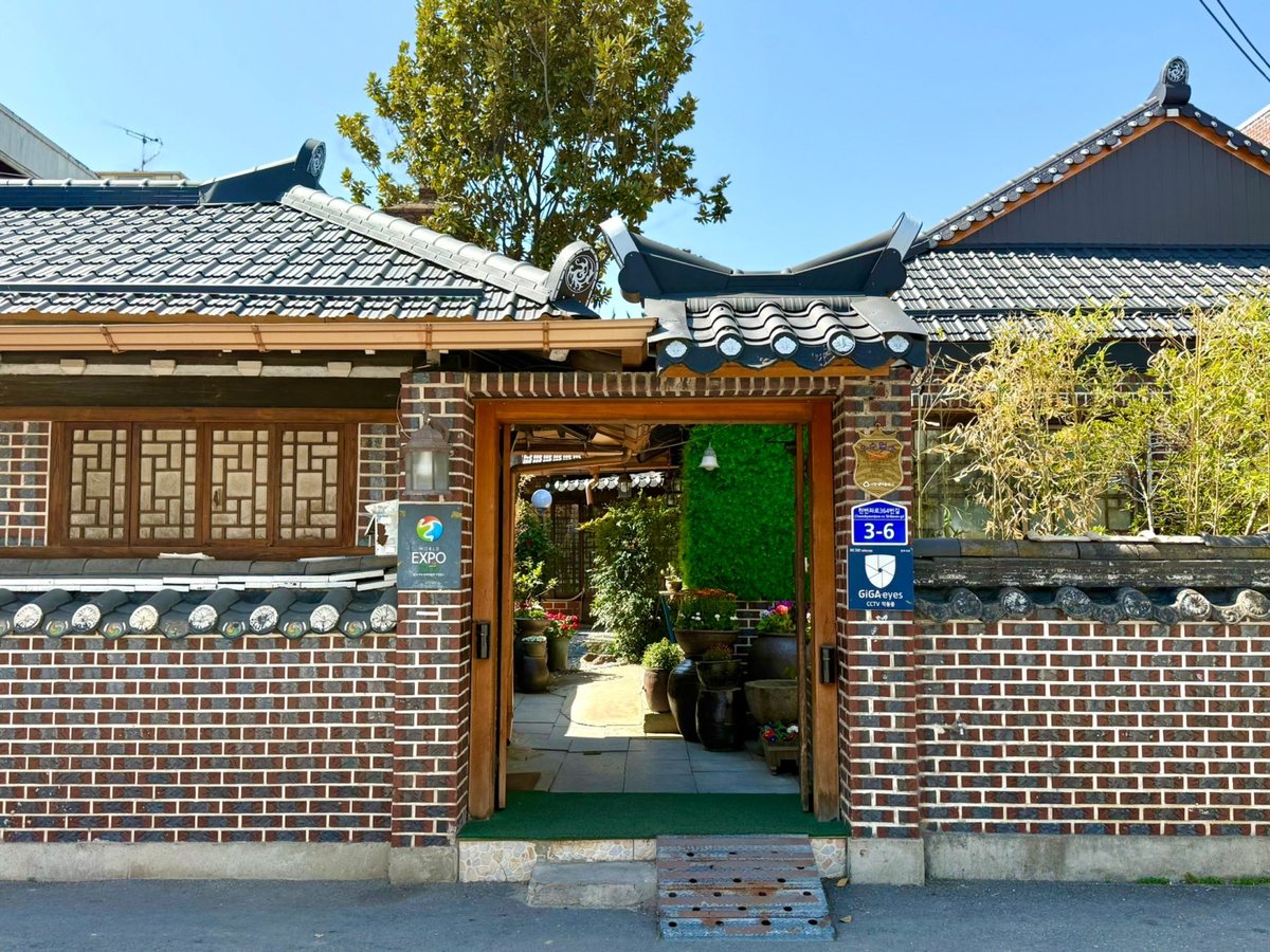 기와지붕과 나무 대문이 있는 거목한정식 한옥 외관