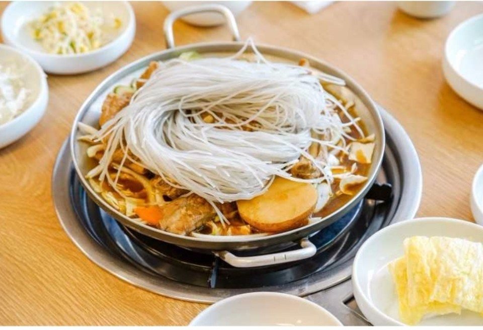 하얀 면 사리와 감자를 올려 끓이는 등갈비찜 냄비와 반찬