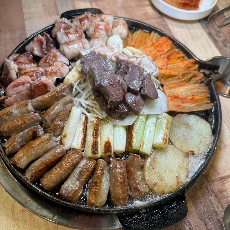 둥근 돌판에 곱창·대창과 대파·감자·김치를 둘러 담은 모듬구이